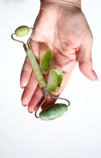  Hand holding green face roller and ice cubes. Derma roller for skin care. - Foto, Imagem
