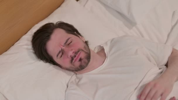 Casual νεαρός άνδρας έχει πονοκέφαλο, ενώ κοιμάται στο κρεβάτι - Πλάνα, βίντεο