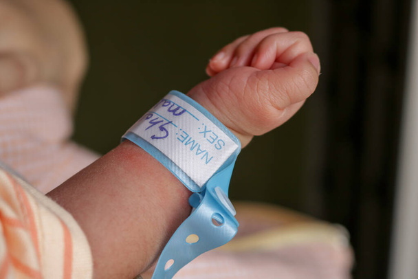 Hand eines Neugeborenen mit Namensband am Handgelenk - Foto, Bild