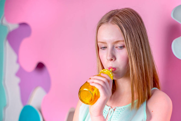 Young blonde in bright t-shirt holding yellow reusable eco water glass bottle. Sweet candy teen blonde girl with blue eyes. - Фото, зображення