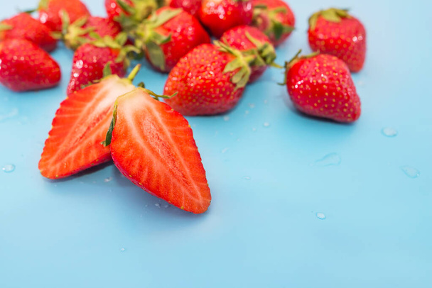 Many sweet ripe strawberries on blue. Sliced berry close-up. Copy space. - Foto, afbeelding