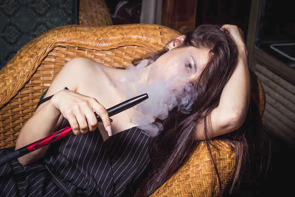 Γυναίκα καπνίζει σεξουαλικά ένα ναργιλέ. Γυναικείο πορτραίτο με κουκούλα - Φωτογραφία, εικόνα