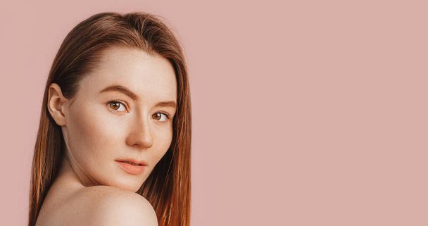 Beautiful sensual young girl with clean skin on a pink background with a mockup. Topless woman in a towel. The concept of spa treatments, natural beauty and care, youth, cream and mask, freshness - Foto, afbeelding
