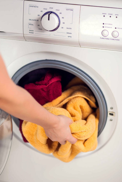 Погрузка одежды в стиральную машину. Домашняя работа, прачечная концепция - Фото, изображение