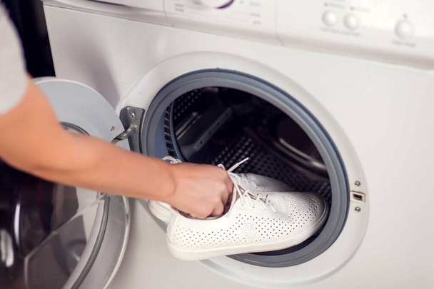 Ładowanie szewców do pralki. Prace domowe, koncepcja prania - Zdjęcie, obraz