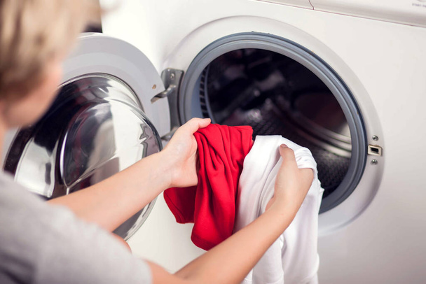 Loading white and color clothes in washing machine. Washing clothes in different colors - Photo, Image