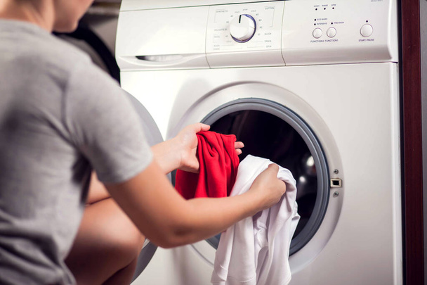 Ładowanie białych i kolorowych ubrań w pralce. Pranie ubrań w różnych kolorach - Zdjęcie, obraz