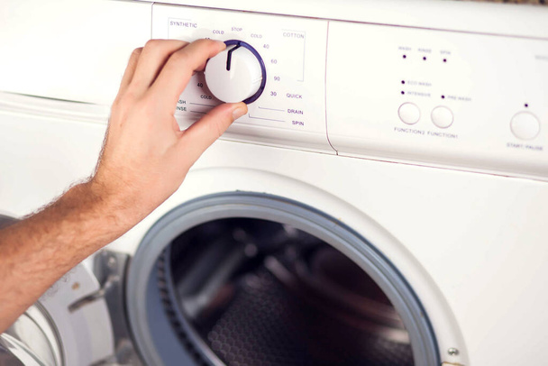 La mano del hombre enciende la lavadora y elige el modo de lavado - Foto, imagen