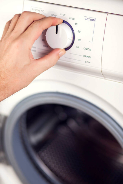 Mužská ruka zapne pračku a zvolí režim praní - Fotografie, Obrázek