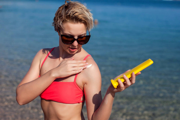 Femme applique une crème de protection solaire sur sa peau. Personnes, soins de santé et concept d'été - Photo, image