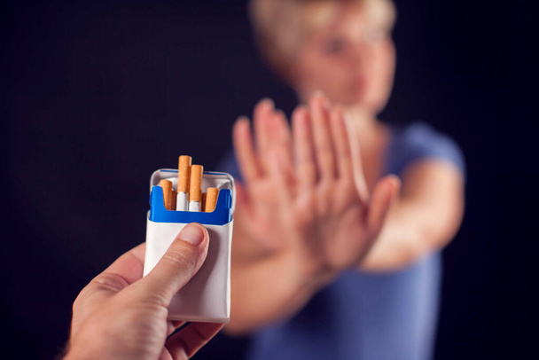 Γυναίκα με μπλε μπλουζάκι που αρνείται τσιγάρα σε μαύρο φόντο. Διακοπή του καπνίσματος - Φωτογραφία, εικόνα