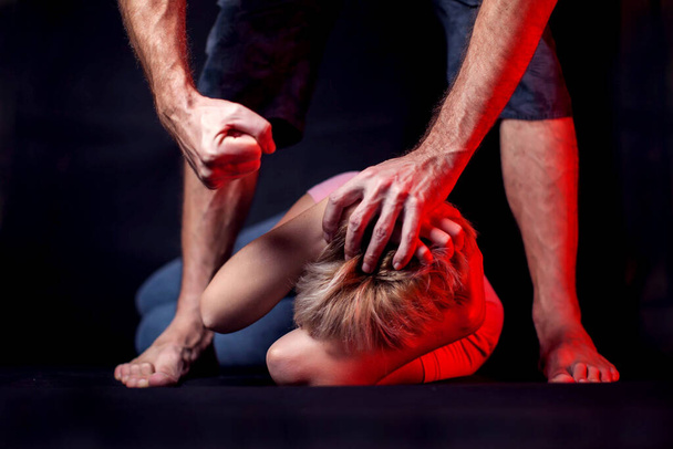 Man beats a woman in front of black background. Family or woman violence concept - Foto, immagini