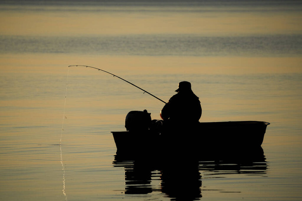 Latvia Fishing boat and fisherman in sea at dawn. - Foto, Imagen