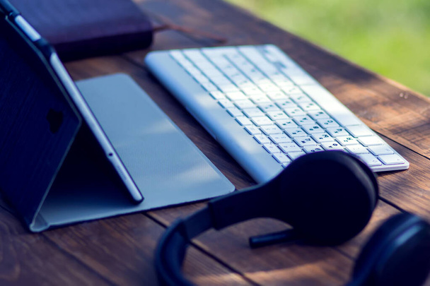 Ακουστικά και laptop είναι στο ξύλινο τραπέζι εξωτερική. Έννοια τεχνολογίας και τρόπου ζωής - Φωτογραφία, εικόνα