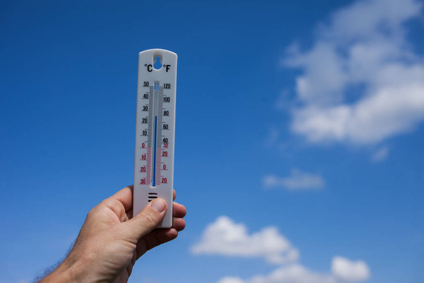 Homem manter termômetro na mão no céu com nuvens de fundo. Conceito meteorológico - Foto, Imagem