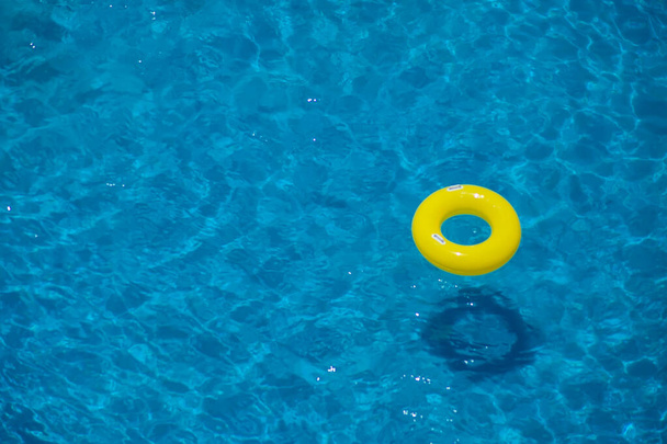 Yüzme havuzunda sarı şişme daire. Yukarı bak. Yaz ve tatil konsepti - Fotoğraf, Görsel