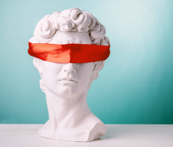 Plaster head with eyes covered red satin ribbon on blue background. Avoid problems concept. - Foto, Bild