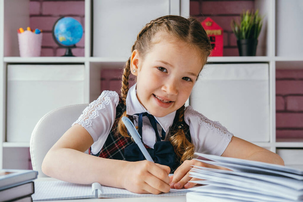 Portrait belle écolière positive assise à son bureau et faisant ses devoirs. Concept de retour à l'école. - Photo, image