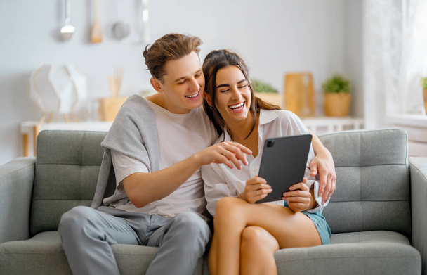 Young couple is using tablet pc. Woman and man having fun staying at home. - Foto, immagini