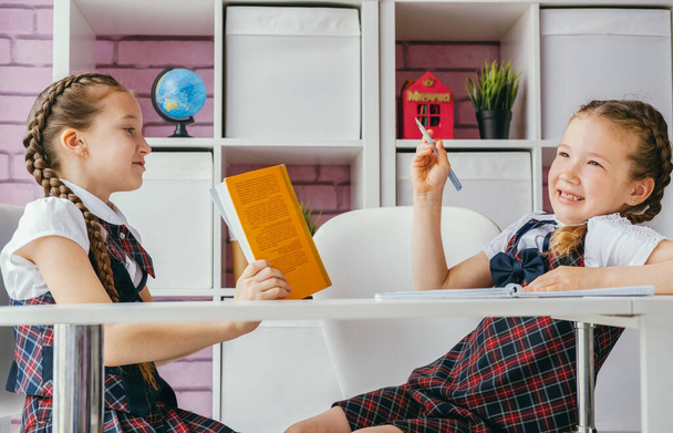 Classmates girls do homework together. A girl reads a book, another girl writes an exercise. - Φωτογραφία, εικόνα