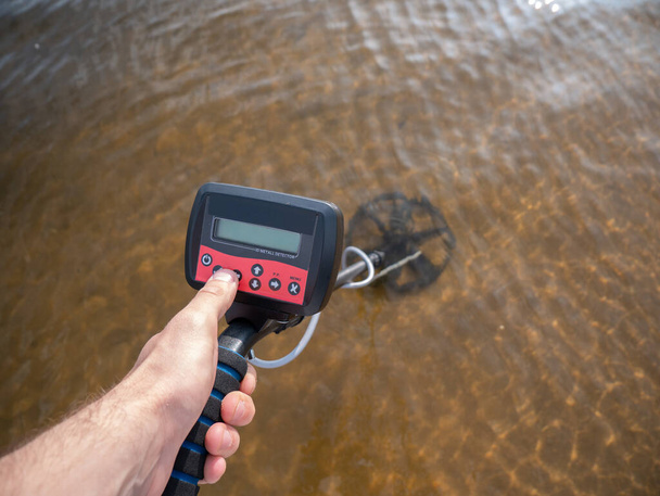 Close-up of a metal detector submerged in water. - Photo, Image