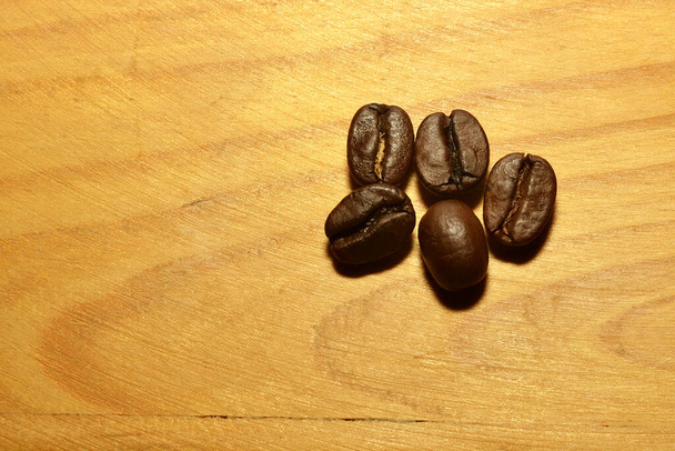 Coffee beans five pieces on a wooden surface - Photo, Image