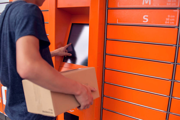 Férfi ügyfél automatizált önkiszolgáló post terminál gép vagy szekrény letétbe egy csomag tárolására - Fotó, kép