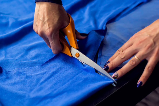 A tailor cuts textile. Manufacture of wearing and fashion concept - Photo, Image
