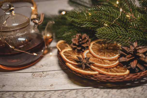 Weihnachtstee mit getrockneten Orangen in einem Korb mit Girlanden und Tannenzweigen und Zapfen. Weihnachtsvormittagskonzept. Flache Lage. - Foto, Bild