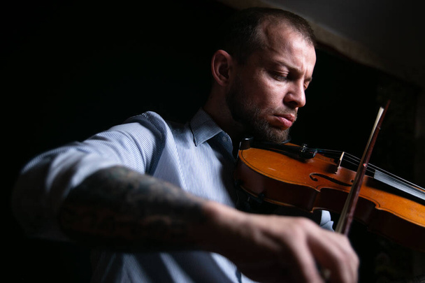 male violinist on a black background plays music on the violin. - Photo, Image
