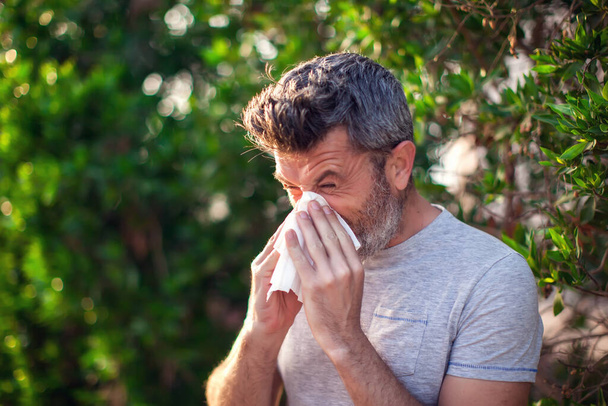 男は木の開花の前で鼻を吹く。春のアレルギーと医療の概念 - 写真・画像