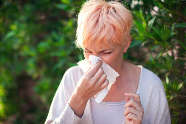Молодая женщина с короткими волосами чихает в ткань. грипп, аллергия, насморк. Люди и концепция здравоохранения - Фото, изображение