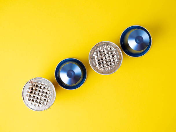 aluminum capsules with ground coffee on a yellow background. several of them are used . The concept of modern solutions for the storage and reuse of products. Top view, flat lay - Foto, Imagen