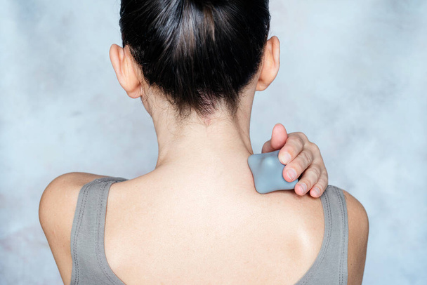 Jonge vrouw masseert haar rug met trigger point bal die diepe weefsel compressie voor snelle, directe verlichting van pijn, pijn en spiervermoeidheid - Foto, afbeelding