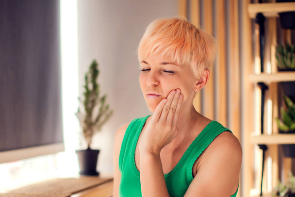 Женщина с болью в зубах держит лицо в помещении. Человек, здравоохранение и медицинская концепция - Фото, изображение