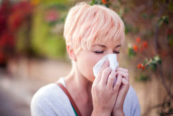 Woman with with allergy symptom blowing nose. Health care and medical concept - Photo, Image