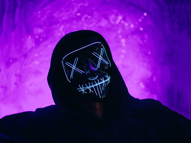 Хэллоуин вечеринка инкогнито в светящемся портрете маски. Фиолетовый фон - Фото, изображение