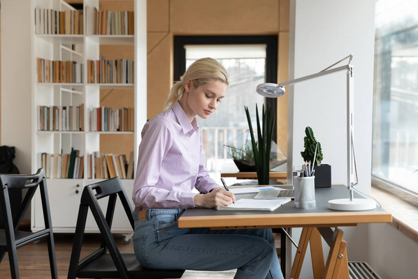 Side view confident businesswoman taking notes, sitting at work desk - Valokuva, kuva