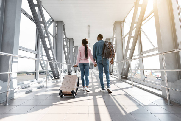 Viaggio di vacanza. Vista posteriore della coppia nera che cammina con il bagaglio in aeroporto - Foto, immagini