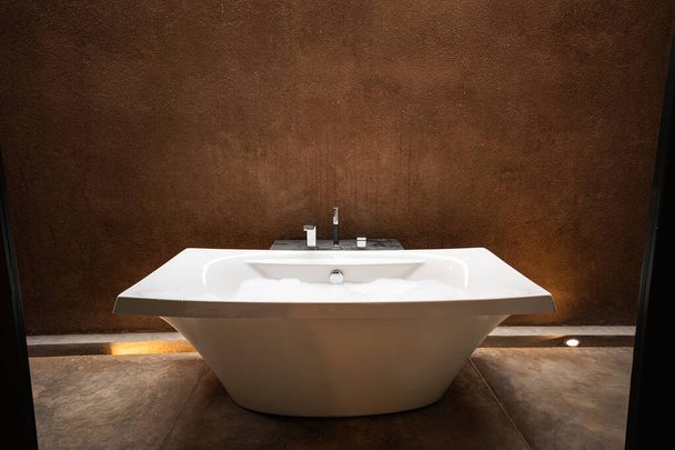 Elegant white ceramic bathtub with bubble in natural earth tone bathroom - Photo, Image