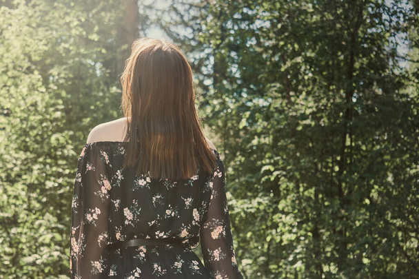 jovem mulher de vestido andando no parque natural ensolarado - Foto, Imagem