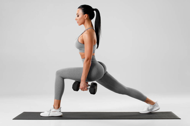 Aktiivinen tyttö tekee syöksyaaltoja harjoituksia jalkojen lihaksen harjoitteluun. Fitness nainen tekee edessä yksi jalka askel syöksy liikunta - Valokuva, kuva