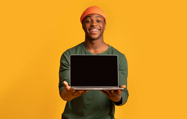Uusi verkkosivusto. Happy Black Hipster Guy osoittaa kannettavan tietokoneen musta ruutu - Valokuva, kuva
