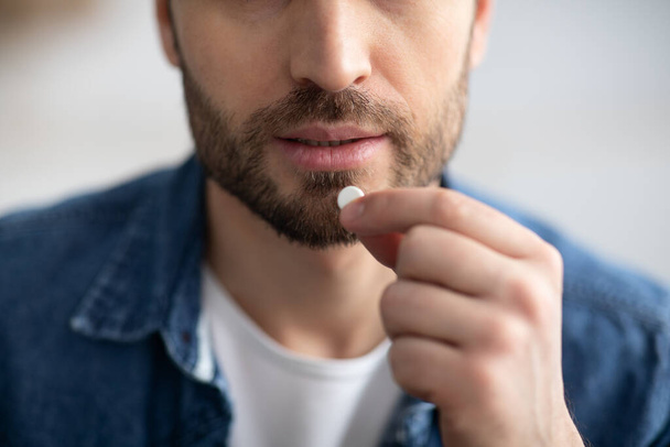 Closeup of bearded man holding medicine in his hand - Photo, Image