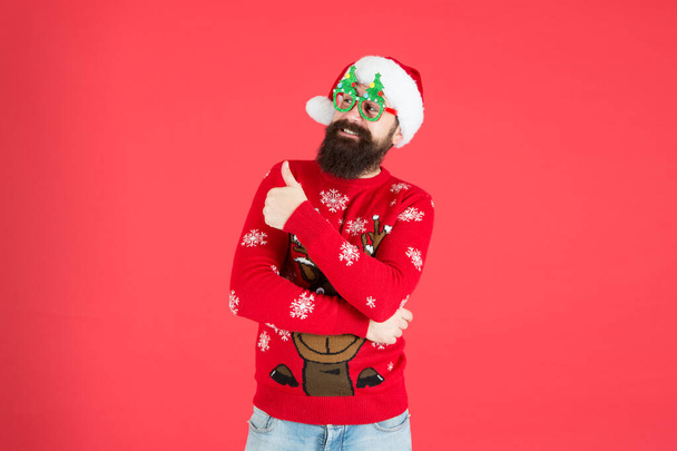 Great holiday specials. winter holiday season. bearded man santa hat red wall. merry christmas. male xmas party glasses. happy new year. funny hipster knitted sweater. warm clothes for cold weather - Photo, image