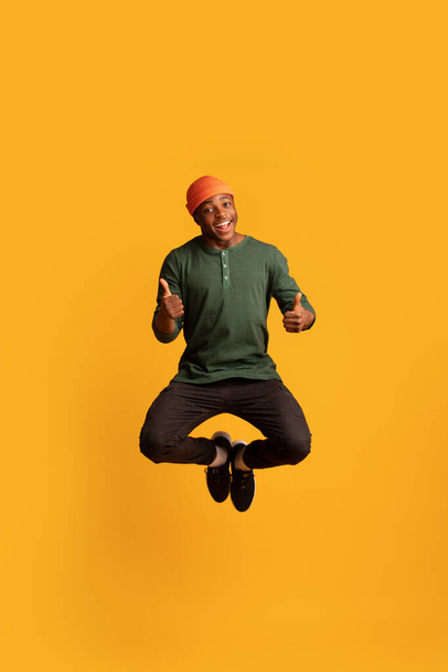 alegre negro hipster chico saltar en aire y mostrando pulgares hasta - Foto, Imagen
