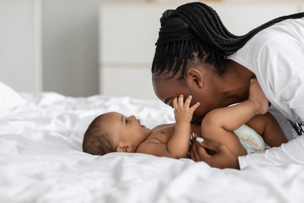 Fekete anya játszik vele csecsemő, csók baba hasában - Fotó, kép
