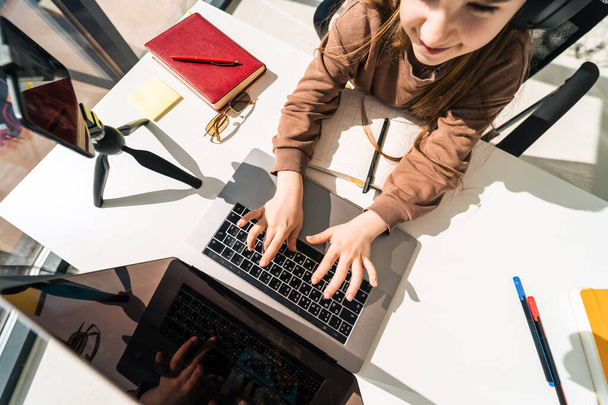 Schattig schoolmeisje aan het werk op laptop. Meisje studeert online - Foto, afbeelding