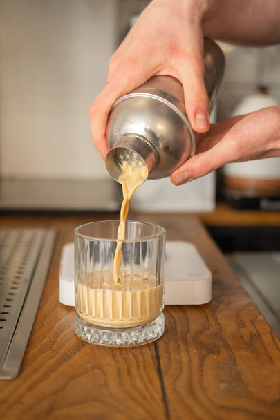 A barista arctalan jeges kávét önt egy rázógépből egy pohárba.. - Fotó, kép