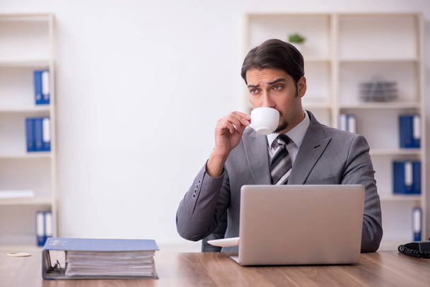 Νεαρός υπάλληλος πίνει καφέ κατά τη διάρκεια του διαλείμματος - Φωτογραφία, εικόνα
